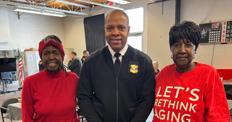 A Cleveland Police commander poses with two community members, one wearing a Benjamin Rose t-shirt, inside Gunning Recreation Center
