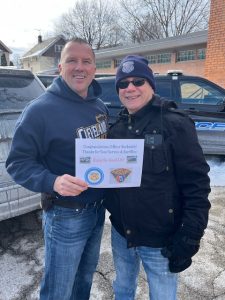 Officer Paul Beckwith and a colleague hold a congratulatory card outside the Second District following his retirement sendoff
