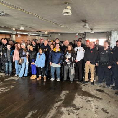 A large group of officers, family, and friends gathered inside the Second District garage to celebrate Officer Paul Beckwith's retirement